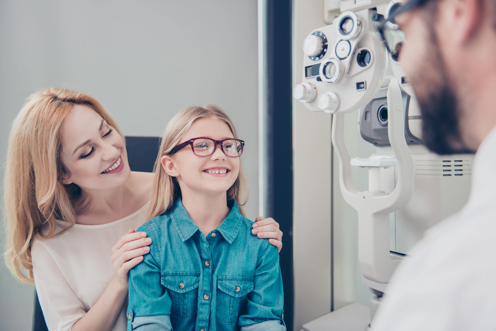 Mother and daughter smiling during a family eye exam with optometrist in Tulsa