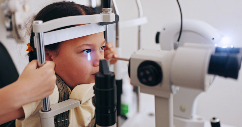 Young girl receiving pediatric eye exam with slit lamp equipment