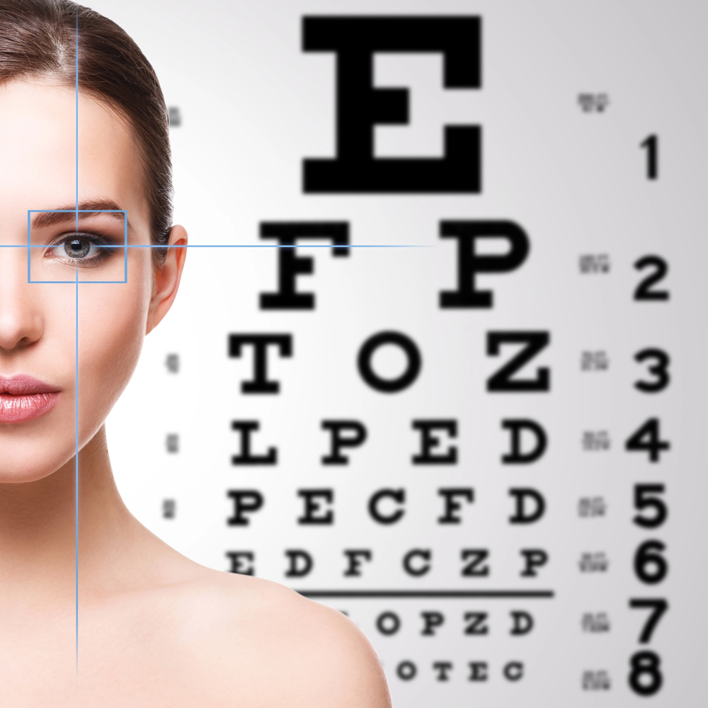Woman smiling during eye exam with vision chart in Tulsa optometry office